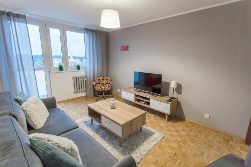 een woonkamer met een blauwe bank en een tv bij Nest Arena Toruń in Toruń