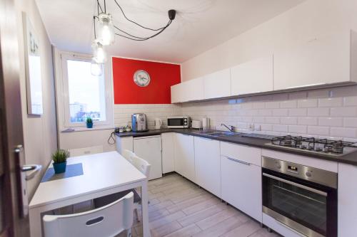 een keuken met witte kasten en een rode muur bij Nest Arena Toruń in Toruń