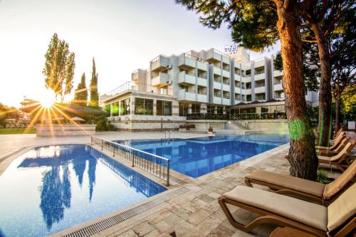 a hotel with a swimming pool with chairs and a building at Hotel Akbulut & Spa in Güzelçamlı