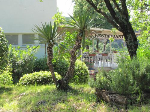 a palm tree in a garden with a restaurant sign at Boarding House Lucija in Kostrena