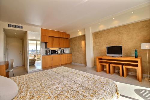 - une grande chambre avec un lit et une télévision dans l'établissement Le Grand Hotel, à Cannes