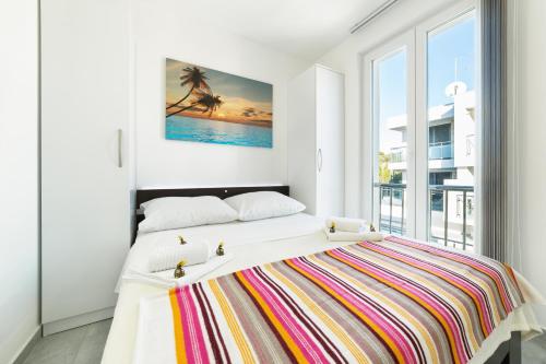 a white bedroom with a large bed with a colorful blanket at Apartments M&L in Vodice