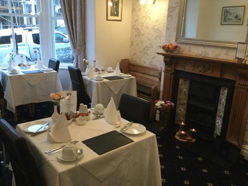 une salle à manger avec deux tables et une cheminée dans l'établissement Dunsford Guest House, à Keswick