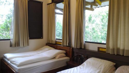 two beds in a room with two windows at Hong Wa Cuo南投埔里紅瓦厝山居民宿 in Puli