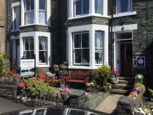 a house with benches and flowers in front of it at Dunsford Guest House in Keswick