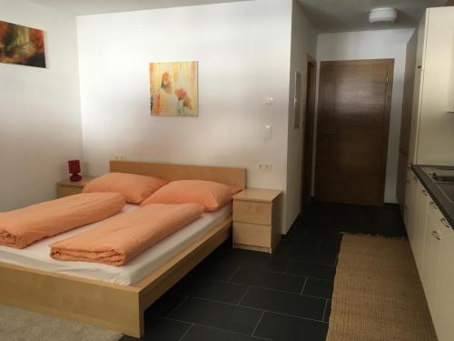 カウナータールにあるHasler Martinaのベッドルーム1室(オレンジ色の枕が付いたベッド1台付)