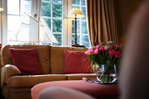a living room with a couch and a vase of flowers at Romantik Manoir Carpe Diem in De Haan