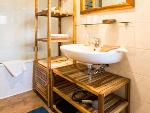 ein Badezimmer mit einem Waschbecken und einem Holzregal in der Unterkunft Wohlfühloase am Weißen Hirsch in Dresden