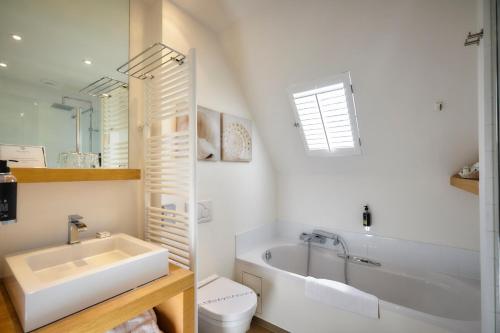 a bathroom with a tub and a toilet and a sink at Romantik Manoir Carpe Diem in De Haan