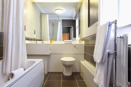 a bathroom with a tub and a toilet and a sink at Derby Midland Hotel, BW Signature Collection in Derby