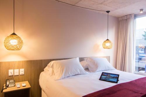a bedroom with a white bed with two pendant lights at Hotel Ciudadano Suites in Montevideo