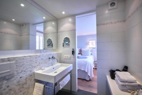 - une salle de bains blanche pourvue d'un lavabo et d'un lit dans l'établissement Romantik Manoir Carpe Diem, au Coq