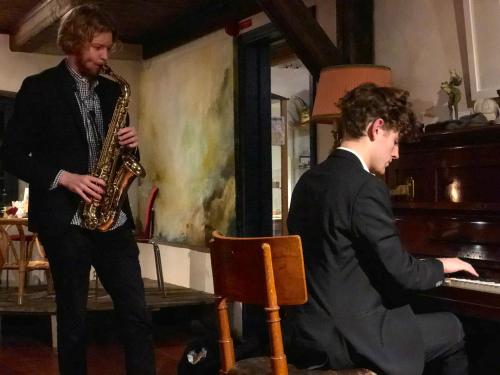 two men playing a saxophone next to a piano at Tryde 1303 B&B på Österlen in Tomelilla