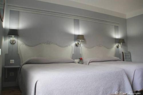a bedroom with two beds with white sheets and lights at Hôtel Majestic in Lourdes