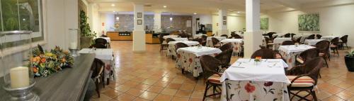 ein Restaurant mit weißen Tischen und Stühlen mit Blumen darauf in der Unterkunft Apartamentos Jardín del Conde in Valle Gran Rey