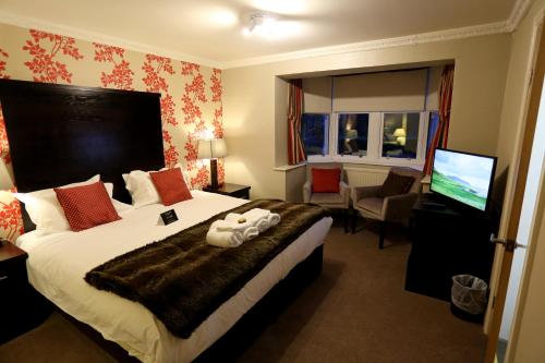 a hotel room with a large bed and a television at Woodlands in Windermere