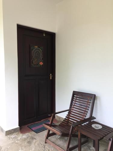 a wooden rocking chair next to a black door at Iwamisou in Sigiriya