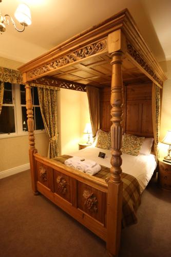 a wooden canopy bed in a room with two lamps at Woodlands in Windermere