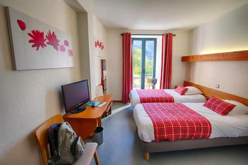 a hotel room with two beds and a television at Auberge du Moulin in Sainte-Énimie