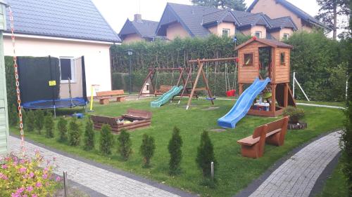 un patio trasero con un parque infantil con un columpio en Liwia, en Niechorze