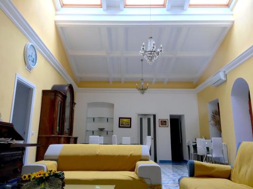 a living room with yellow couches and a chandelier at Arte & Mare in Patti