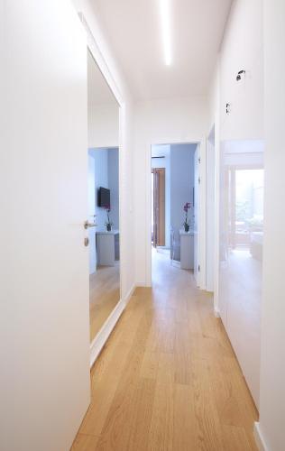 a hallway with white walls and wood floors and a mirror at Luxury Apartment Kampanel in Split