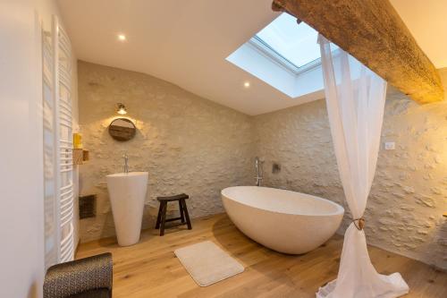 a bathroom with a large tub and a sink at Le Vallon De Guerry in Sainte-Colombe-de-Duras