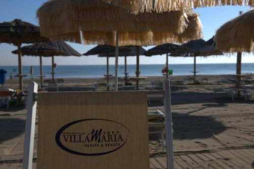 a sign on a beach with straw umbrellas at Villa Maria Hotel & SPA in Francavilla al Mare
