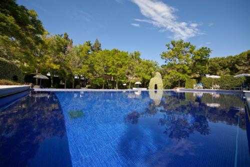 a large blue swimming pool with trees in the background at Villa Maria Hotel & SPA in Francavilla al Mare
