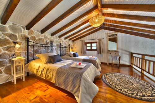 a bedroom with two beds and a stone wall at Glyfada Beach Villas in Longos