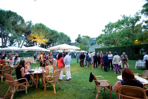 a crowd of people sitting around tables in a park at Villa Maria Hotel & SPA in Francavilla al Mare