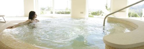 a woman sitting in a hot tub in a room at Villa Maria Hotel & SPA in Francavilla al Mare