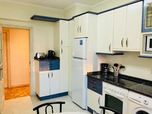eine Küche mit weißen Schränken und einem weißen Kühlschrank in der Unterkunft Apartamento Vitoria II in Vitoria-Gasteiz