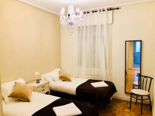 a bedroom with two beds and a chandelier at Apartamento Vitoria II in Vitoria-Gasteiz