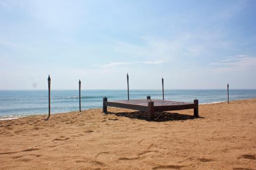 a bench sitting on the beach near the ocean at Mumsa Beach Resort & Restaurant in Ban Huai Yang
