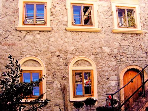 a stone building with four windows on it at Living History (adults only) in Hallstatt