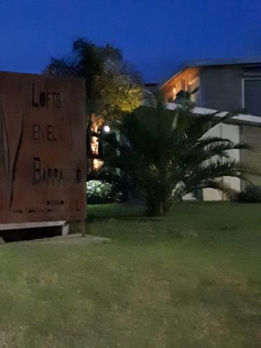 a sign in front of a building with a palm tree at Loft del barranco in Colonia del Sacramento