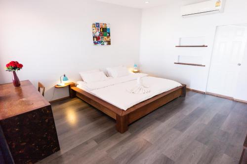 a bedroom with a bed with white sheets and a wooden floor at Mumsa Beach Resort & Restaurant in Ban Huai Yang