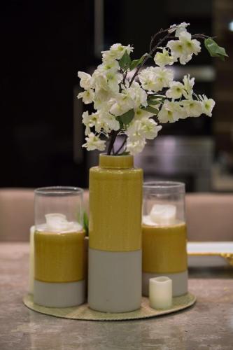 a vase with flowers and candles on a table at شالية النخلة in Unayzah