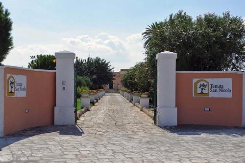 a stone walkway leading to a building with a fence at Tenuta San Nicola in Novoli