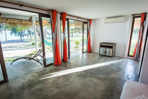 an empty room with orange curtains and sliding glass doors at Mumsa Beach Resort & Restaurant in Ban Huai Yang
