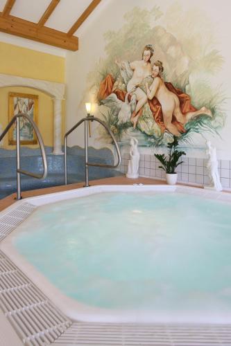 a large tub in a room with a painting on the wall at Wellness- und Vitalhotel Böhmhof in Bodenmais