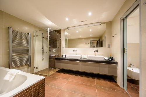 een badkamer met 2 wastafels, een bad en een douche bij President APT by Prague Castle, VIEWS in Praag