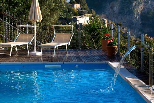a pool with two chairs and a water fountain at Villa Gioiello in Amalfi