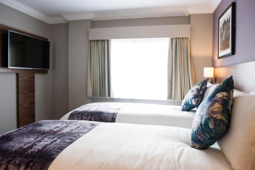 a hotel room with two beds and a window at The Swan by Innkeeper's Collection in Coleshill