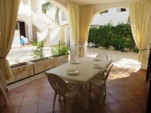 una mesa y sillas blancas en una habitación con ventana en Residence Giglio, en Torre Pali