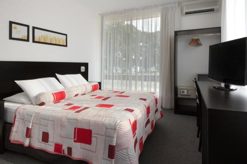 a bedroom with a bed and a desk and a television at Gran Hotel Fray Bentos in Fray Bentos