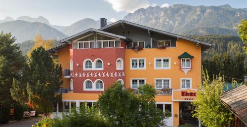 a large orange building with mountains in the background at Bliem's Familienhotel in Haus im Ennstal