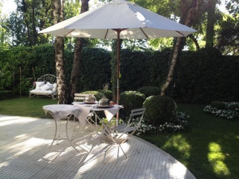 a table and chairs under an umbrella in a garden at Casa Cuniolo Guest House in Tortona