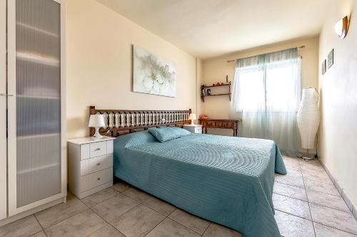 Un dormitorio con una cama con edredón azul y una ventana. en Apartment Americos El Dorado, en Playa de las Américas